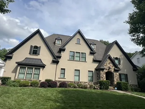 Stucco home with stone entry and freshly painted black fascia and trim
