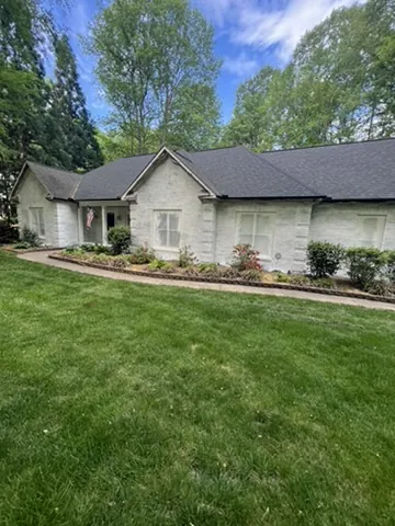 Brick ranch home painted white with green shutters