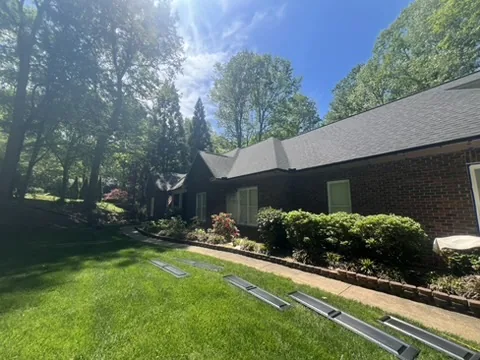 Red brick ranch home with green shutters before exterior painting