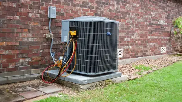Outdoor AC unit installed against a brick wall