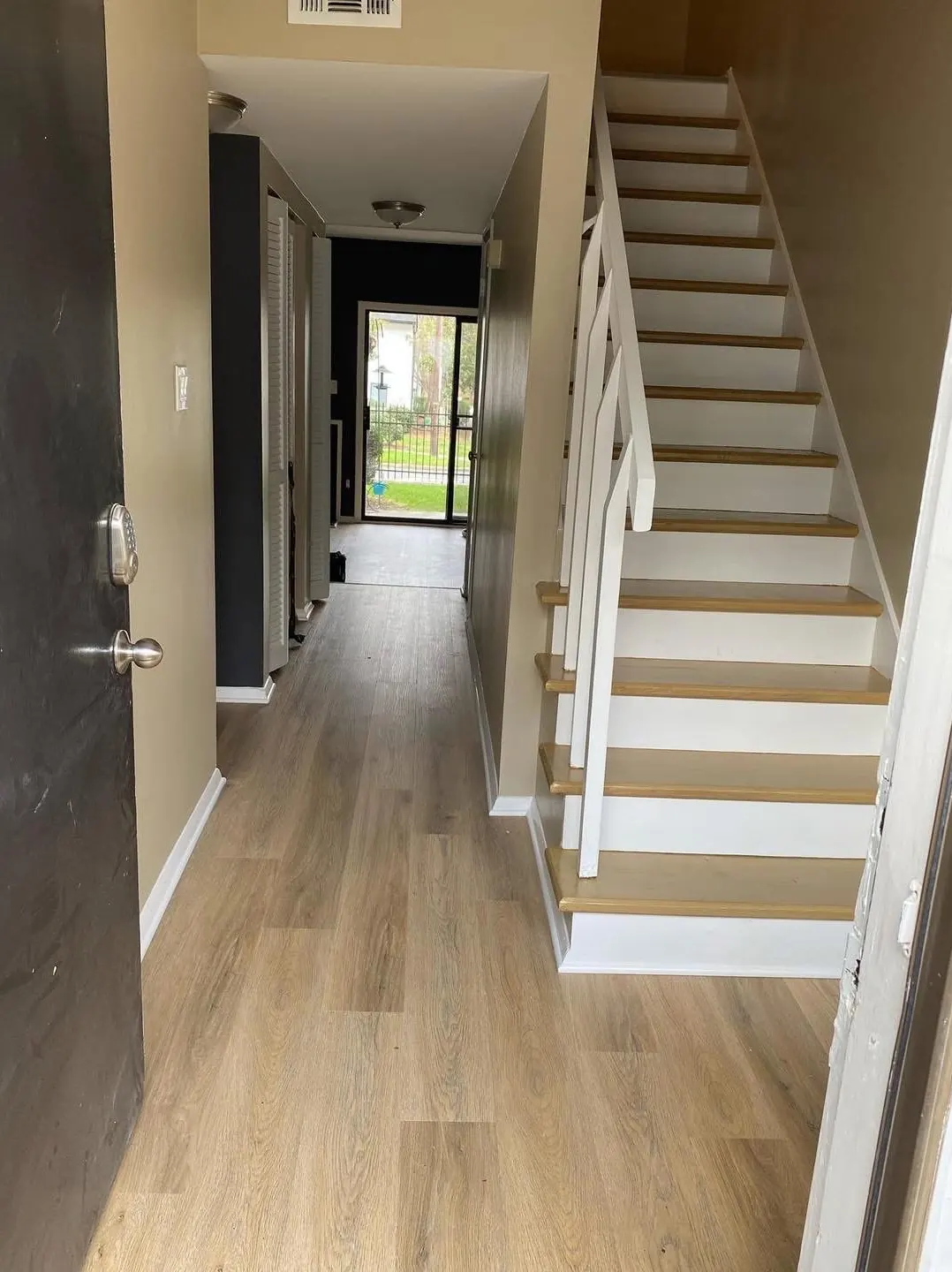 Entryway after: walls repainted, stair risers and trim painted white, new floor