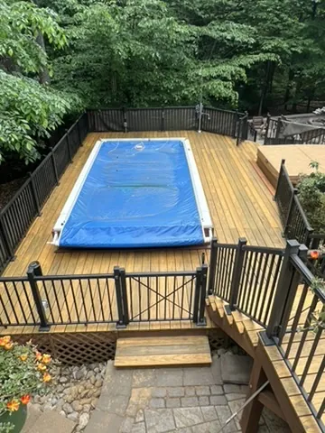 Pool deck with freshly stained wood boards and black aluminum railing