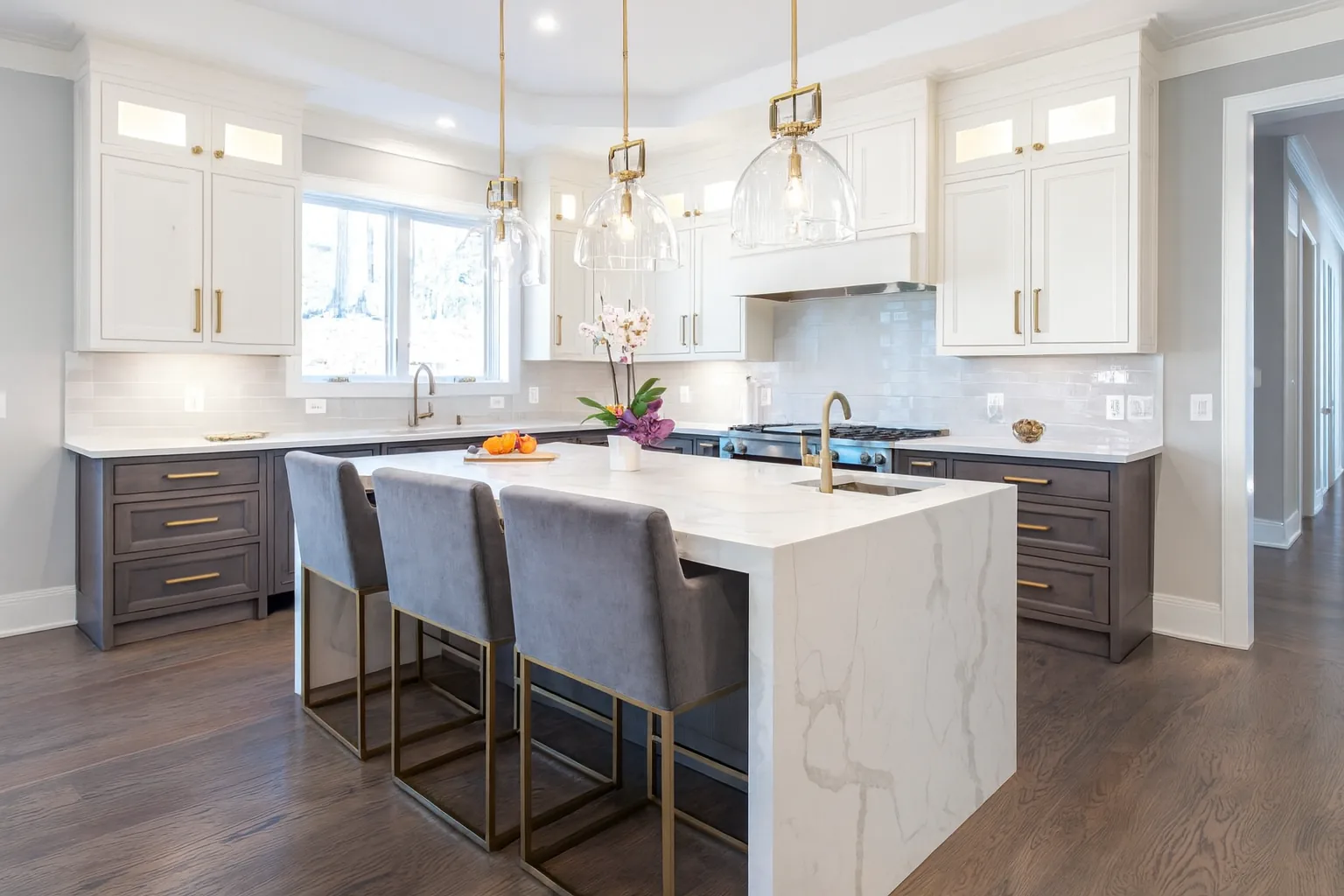 White kitchen remodel with waterfall quartz island and pendant lights